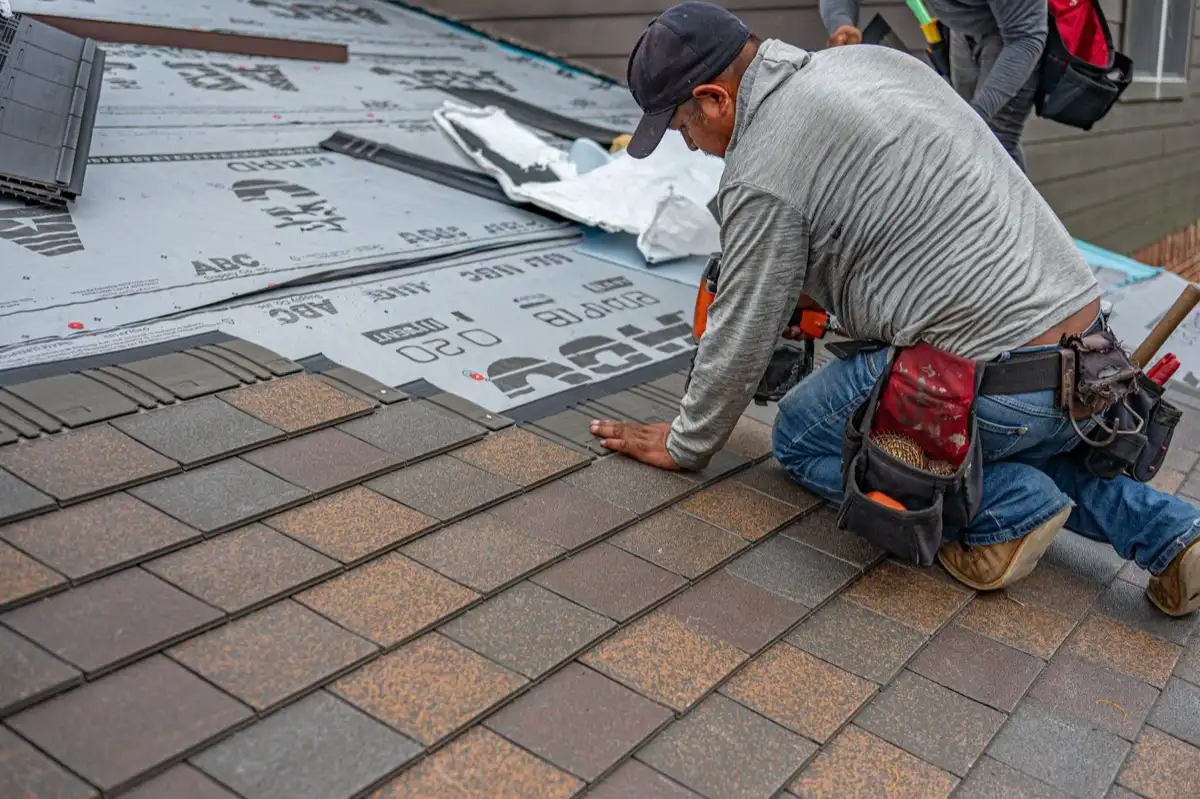 Roofing installer fastening shingles over new underlayment in Ontario, CA